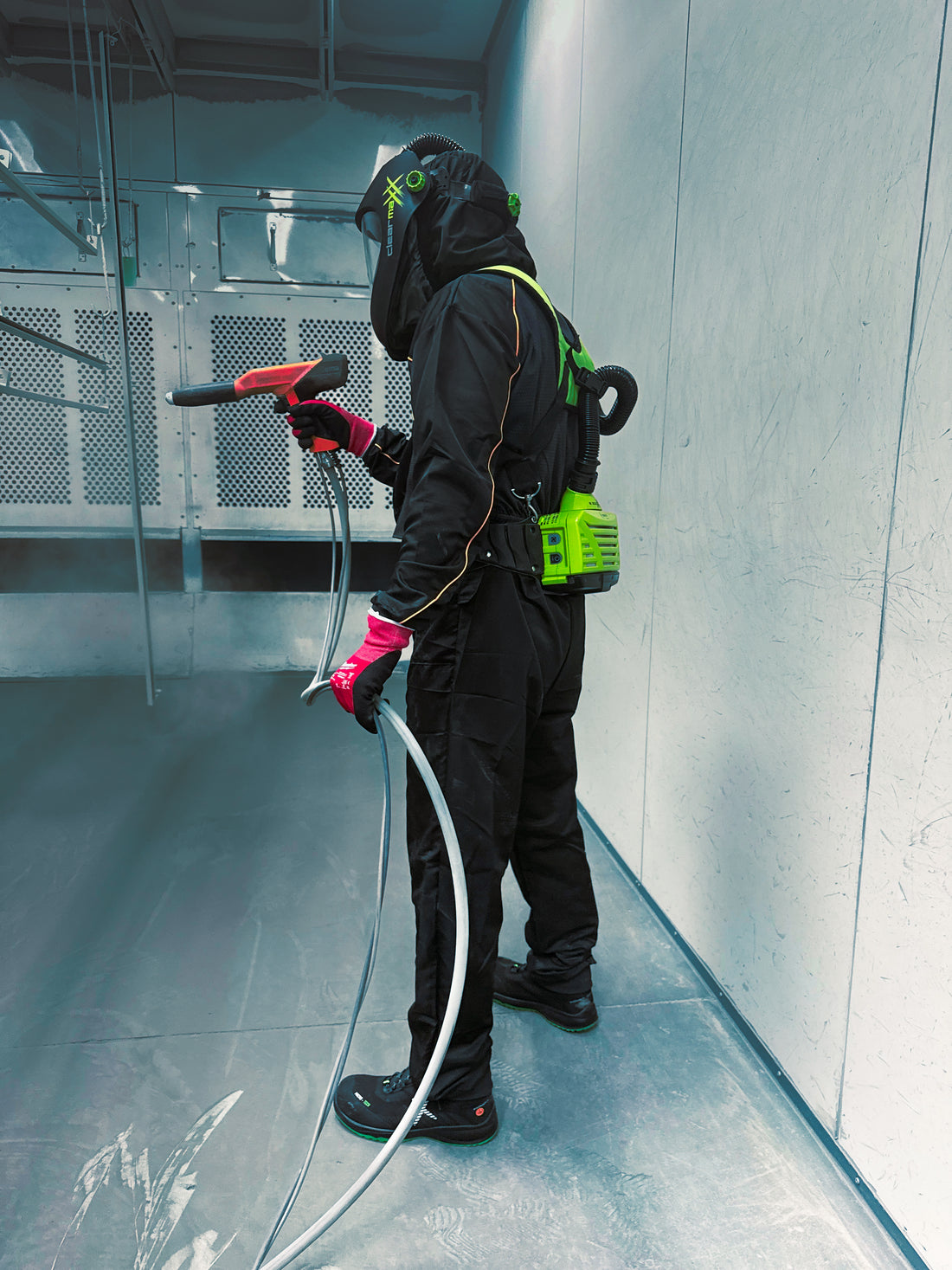 Peintre équipé du kit complet Clearmaxx : cagoule Clearmaxx, turbo e3000X, combinaison, gants et chaussures de sécurité en cabine